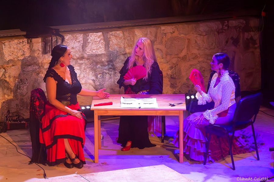 Escena de teatro: tres mujeres en torno a una mesa
